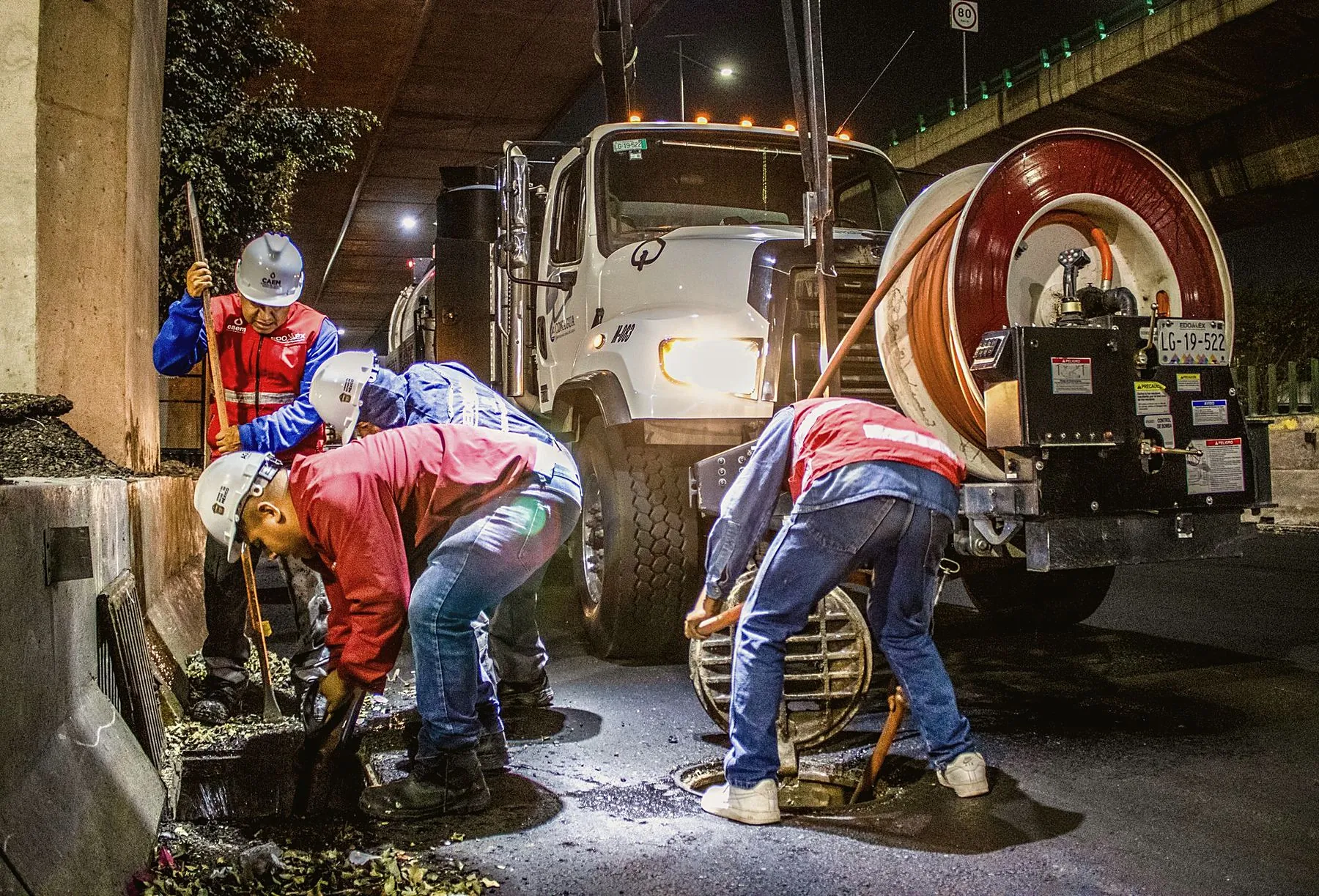 Night crew clearing a storm drain with a vacuum truck