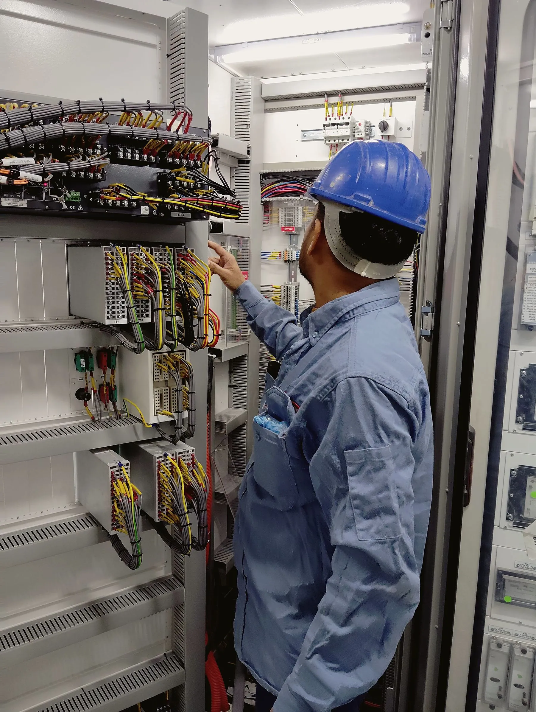 Electrician in a hard hat working a switchgear cabinet