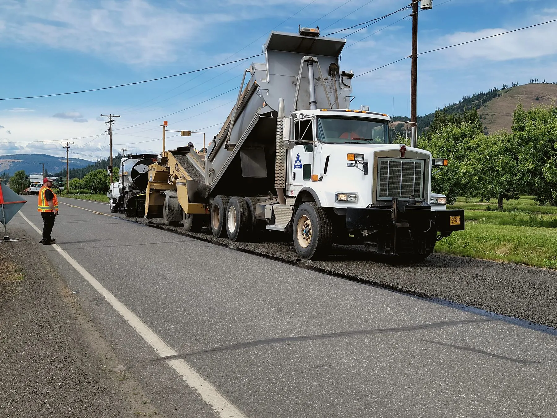 Paving crew and dump truck on a road resurfacing job