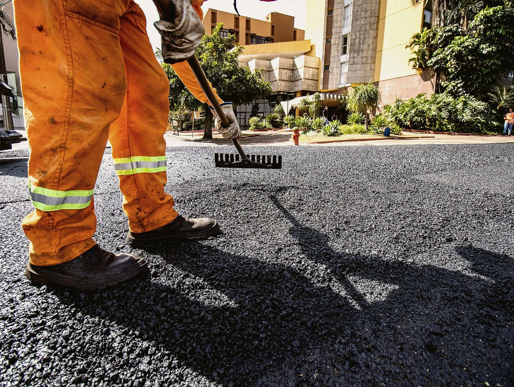 Worker raking fresh asphalt