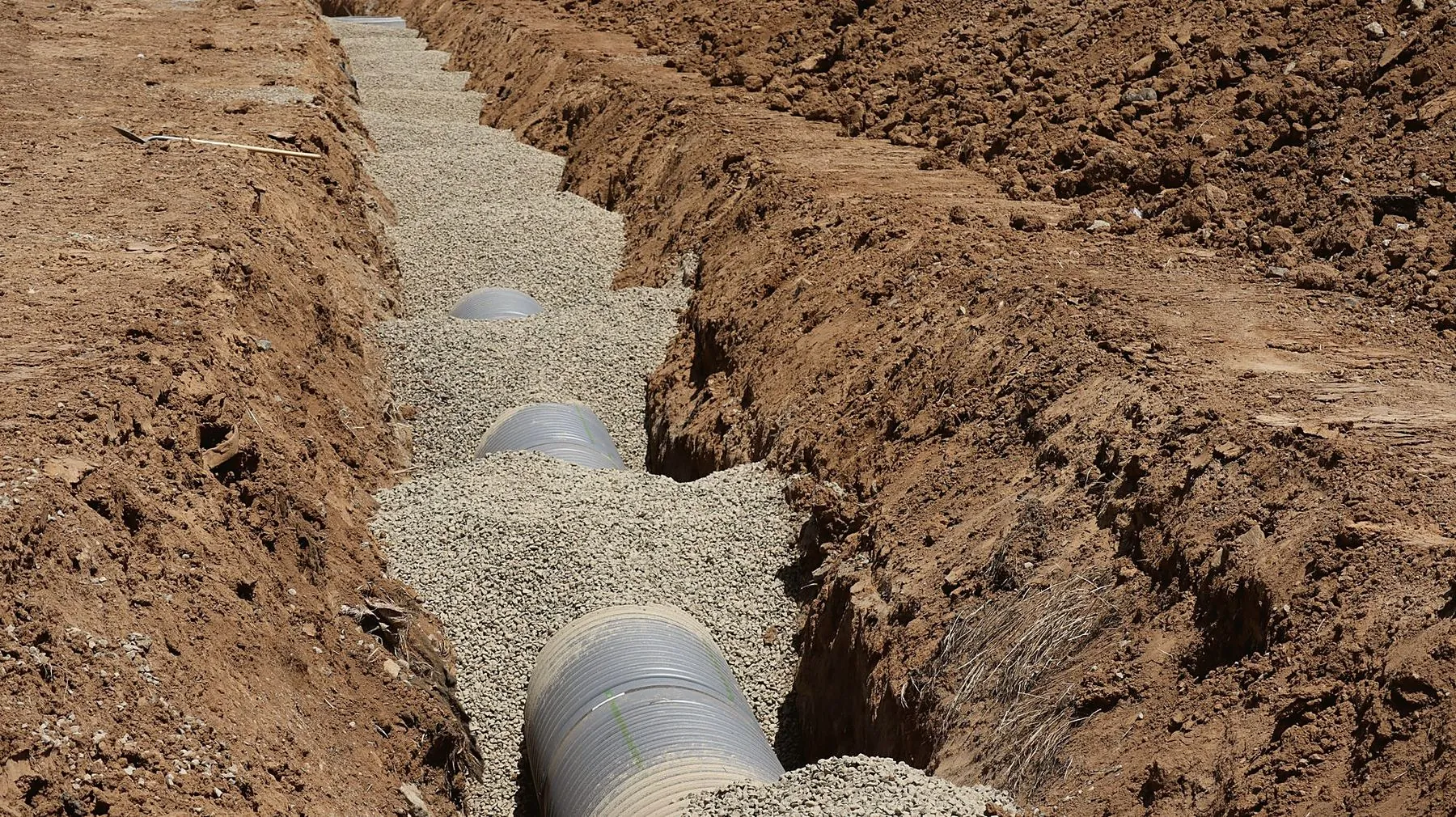 Pipe laid on gravel bedding in a shored trench in California